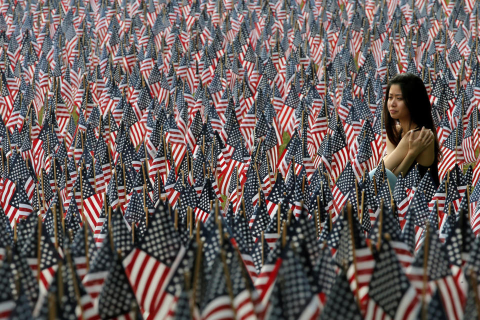 A woman sits at the edge of the field of United States flags displayed by the Massachusetts Military Heroes Fund on the Boston Common in Boston, Massachusetts on May 26, 2016.