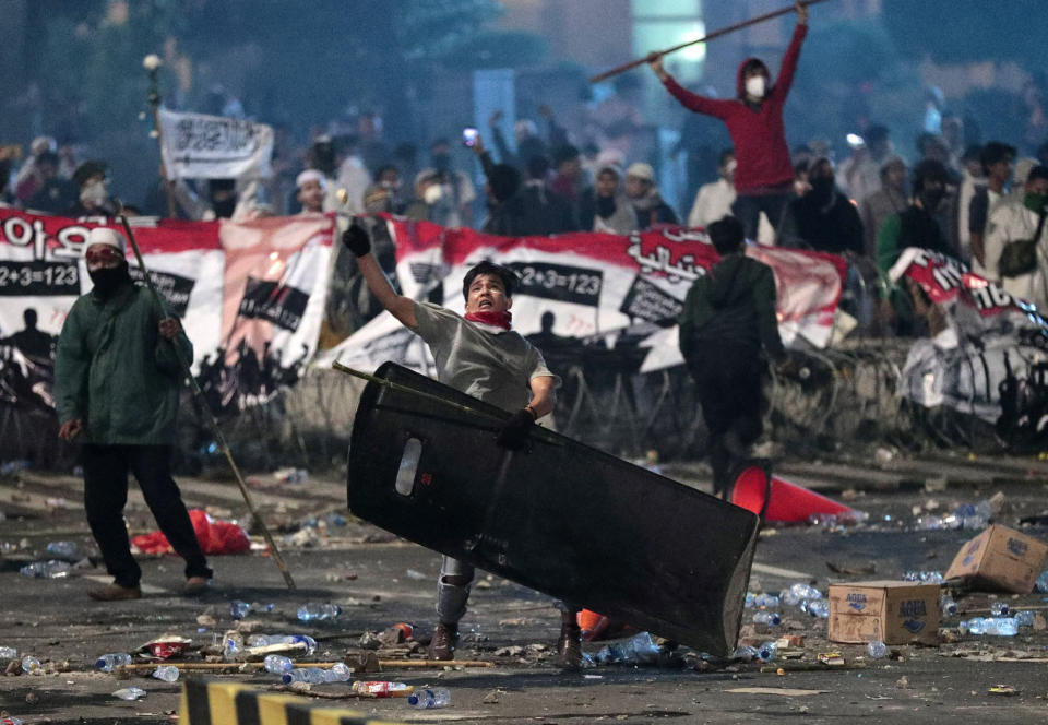 A supporter of Indonesian presidential candidate Prabowo Subianto throws rock at riot police during clashes in Jakarta, Indonesia, Wednesday, May 22, 2019. Indonesian President Joko Widodo said authorities have the volatile situation in the country's capital under control after six people died Wednesday in riots by supporters of his losing rival in last month's presidential election. (AP Photo/Dita Alangkara)