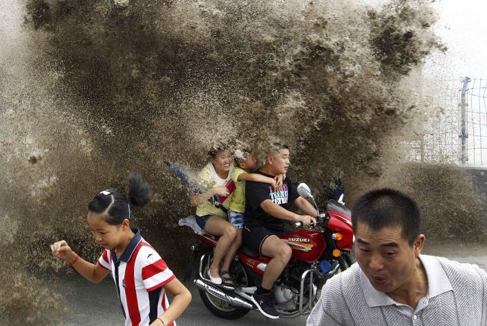 RNPS - REUTERS NEWS PICTURE SERVICE - PICTURES OF THE YEAR 2014 Visitors run away as waves caused by a tidal bore surge past a barrier on the banks of Qiantang River, in Hangzhou, Zhejiang province, in this August 13, 2014 file photo. REUTERS/Stringer/Files (CHINA - Tags: SOCIETY ENVIRONMENT TPX IMAGES OF THE DAY) CHINA OUT. NO COMMERCIAL OR EDITORIAL SALES IN CHINA