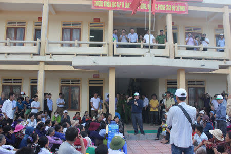 Catholic Priest Anthony Dang Huu Nam (C) talks with Vietnamese fishermen waiting outside the people's court as they prepare to sue Formosa Ha Tinh Steel, a subsidiary of Taiwan's Formosa Plastics, over an accident at one of its steel plant which caused massive fish deaths along a 200km (120 mile) stretch of coastline, in Vietnam's central province of Ha Tinh, September 26, 2016. Handout via REUTERS