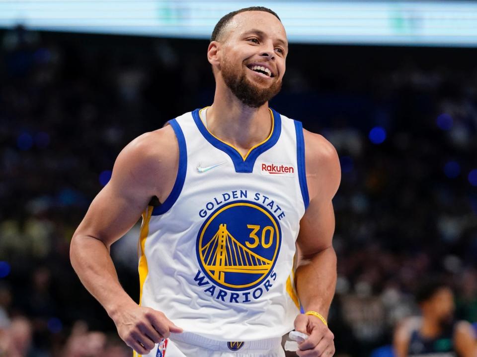 Stephen Curry smiles as he runs on the court.