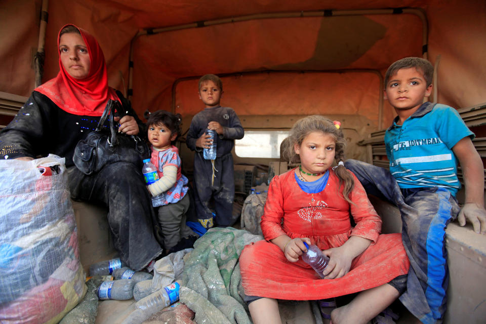 Displaced people sit in a military vehicle in Qayyarah