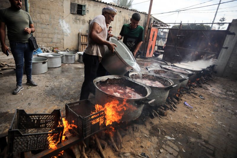 Palestinian men prepare food in large pots simmering on wooden fires due to the lack of cooking gas in Rafah in the southern Gaza Strip on Saturday as Israel announced the war had entered a 'new phase.' Photo by Ismael Mohamad/UPI