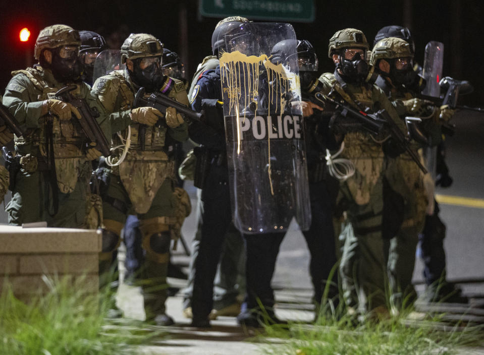 Police confront protesters outside the U.S. Immigration and Customs Enforcement office in Portland, Ore., Thursday, Aug. 20, 2020. Portland police say people in a group of about 100 late Thursday and early Friday sprayed the building with graffiti, hurled rocks and bottles at agents and shined laser lights at them.(Mark Graves /The Oregonian via AP)