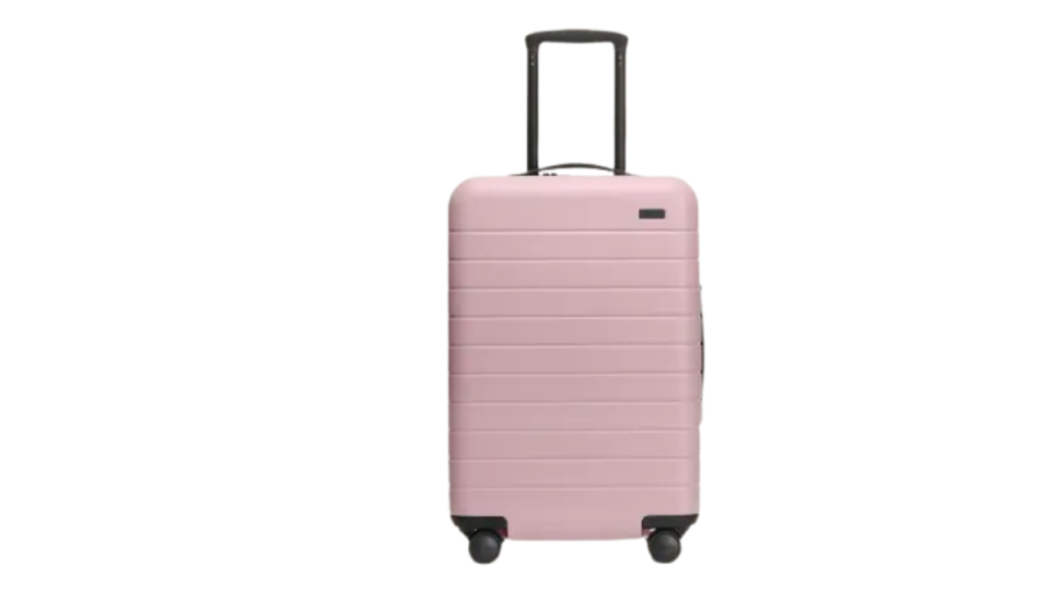 Light pink hard sided rolling Away Travel suitcase with black handle and wheels. 