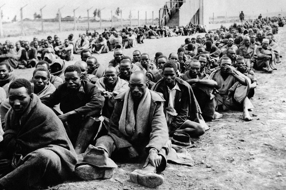 Some of the many Kikuyu tribesmen who were detained as Mau Mau suspects after the forced evacuation of Kikuyus accused of squatting on European farms in the Thomson’s Falls area, Kenya, wait to be transported on Nov. 30, 1952. (AP Photo, File)