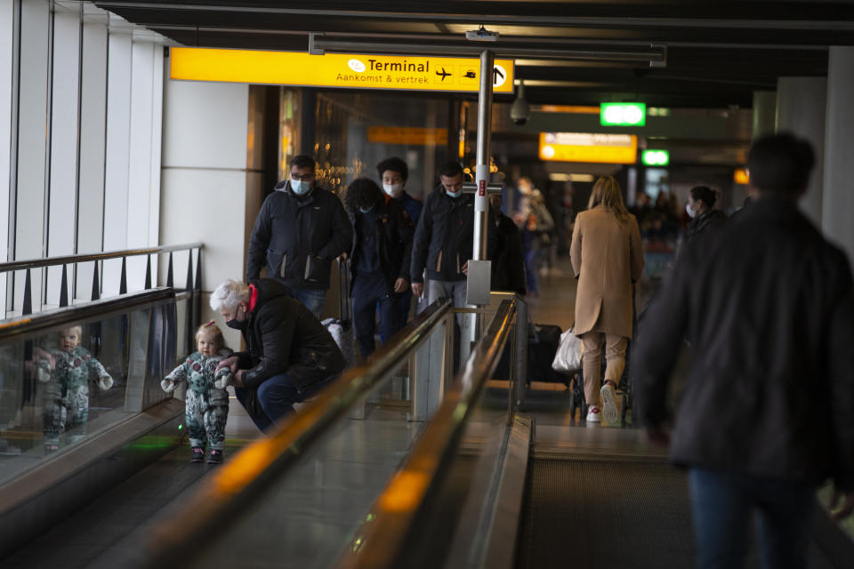 FILE- In this Friday Dec. 18, 2020, file photo, arriving and departing passengers use the flat escalators at Schiphol Airport, near Amsterdam, Netherlands. The Netherlands is banning flights from the United Kingdom for the rest of the year in an attempt to make sure that a new strain of the COVID-19 virus in Britain does not reach its shores. The ban came into effect Sunday morning Dec. 20, 2020, and the government said it was reacting to tougher measures imposed in and around London on Saturday. The Netherlands said it will assess "with other EU nations the possibilities to contain the import of the virus from the United Kingdom." (AP Photo/Peter Dejong, FILE)