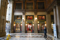FILE - In this Friday, Nov. 20, 2020 file photo, a security guard stands outside an almost empty Christmas decorations shop, in Rome. Nations are struggling to reconcile cold medical advice with a holiday tradition that calls for big gatherings in often poorly ventilated rooms, where people chat, shout and sing together, providing an ideal conduit for a virus that has killed over 350,000 people in Europe so far. (AP Photo/Andrew Medichini, File)