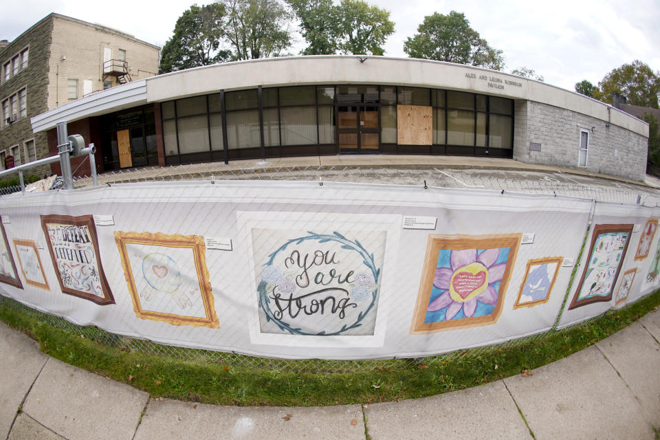 This photo from Oct. 16, 2021, shows the dormant landmark Tree of Life synagogue with the fencing showing artwork submitted by Pittsburgh area school students in Pittsburgh's Squirrel Hill neighborhood. Renowned architect Daniel Libeskind is among those working to transform the site to share space with the Holocaust Center of Pittsburgh. The goal to create a solemn memorial as well as a place of regular activity is underway as the date marking the third year since 11 people were killed in America's deadliest antisemitic attack on Oct. 27, 2018 approaches. (AP Photo/Keith Srakocic)