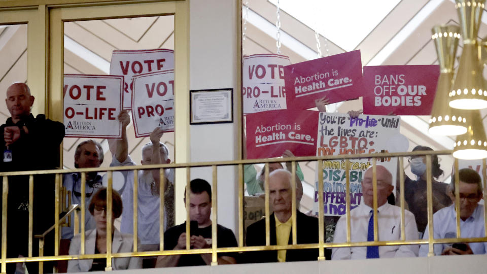 Protesters on both sides of the issue hold signs as North Carolina House members debate, Tuesday, May 16, 2023, in Raleigh, N.C., on whether to override Democratic Gov. Roy Cooper's veto of a bill that would change the state's ban on nearly all abortions from those after 20 weeks of pregnancy to those after 12 weeks of pregnancy. Both the Senate and House had to complete successful override votes for the measure to be enacted into law. The Senate voted to override the veto earlier and the House also voted to override. (AP Photo/Chris Seward)