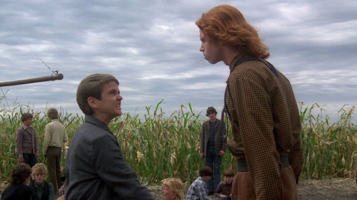 two menacing figures talk in front of a corn field in a scene from 'children of the corn,' a good housekeeping pick for best halloween movies