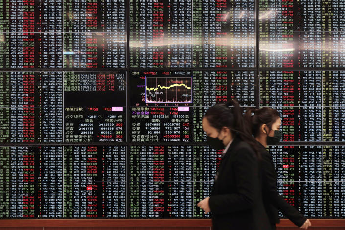 People walk past an electronic stock board at Taipei Exchange in Taipei, Taiwan, Monday, Jan. 30, 2023. Shares were trading mixed in Asia on Monday after Wall Street benchmarks closed higher on Friday, capping a third week of gains out of the last four. (AP Photo/Chiang Ying-ying)