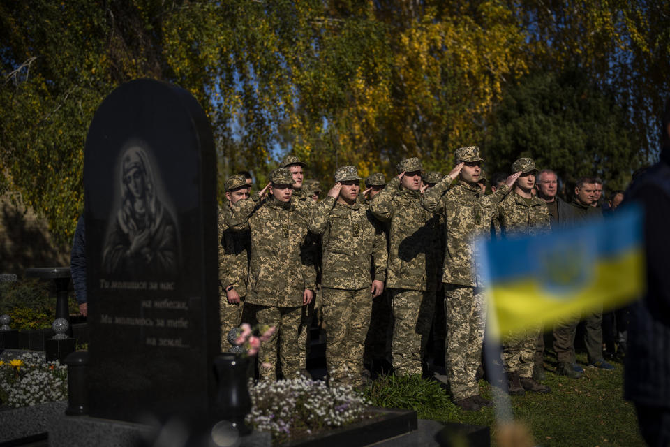 Soldiers salute as the Ukrainian national anthem is played at the funeral of Colonel Oleksiy Telizhenko in Bucha, near in Kyiv, Ukraine, Tuesday, Oct. 18, 2022. In March, Colonel Oleksiy was abducted by Russian soldiers from his home in Bucha, six months later his body was found with signals of torture buried in a forest not far away from his village. (AP Photo/Emilio Morenatti)