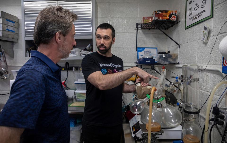 Jim Weyman, left, listens to Eric Parkhurst, grower and founder of Winewood Organics, as he explains a part of the cooking process for the edibles and other cannabis products during a cannabis tour inside Winewood Organics in Ann Arbor on Saturday, Sept. 30, 2023.