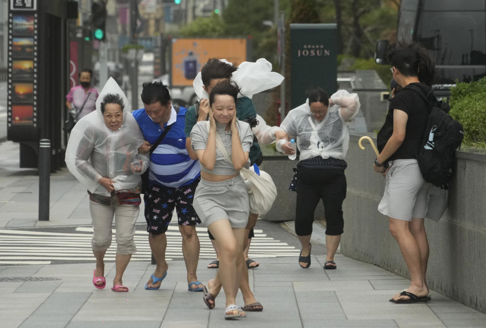 People struggle in the rain and wind as the tropical storm named Khanun approaches to the Korean Peninsular, in Busan, Thursday, Aug. 10, 2023. (AP Photo/Ahn Young-joon)