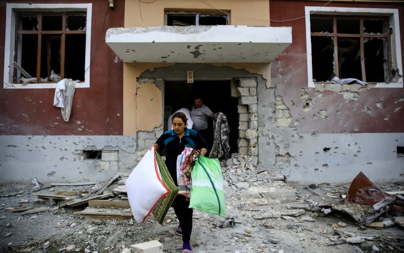 Residents carry their belongings from their damaged home after a ceasefire began during the fighting over the breakaway region of Nagorno-Karabakh in the city of Terter