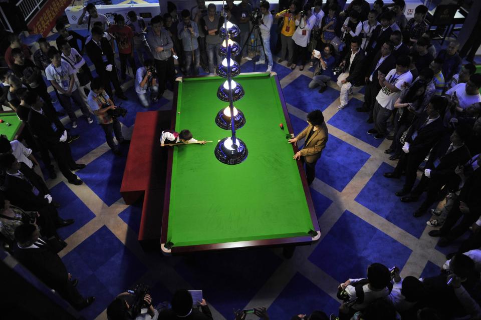 Three-year-old Wang Wuka (on L of table) plays snooker with seven-time World Championship winner Stephen Hendry (not pictured) of Britain in Beijing, September 22, 2013. (REUTERS/Stringer)