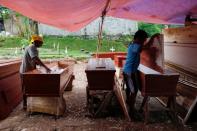 Coffins makers Suherman, 45-year-old, and Ari Rusmawan, 32-year-old, prepare coffins ordered to be donated for the coronavirus disease (COVID-19) victims at a workshop inside a funeral complex in Jakarta