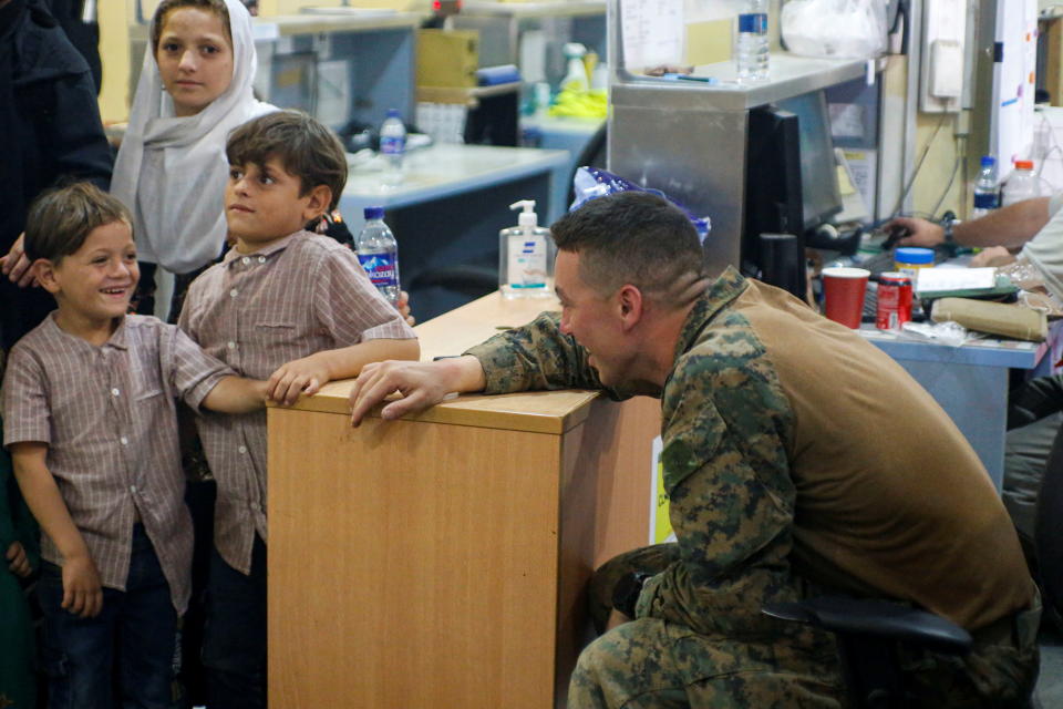 A U.S. Marine assigned to 24th Marine Expeditionary Unit interacts with children during an evacuation at Hamid Karzai International Airport, Afghanistan, August 18, 2021. (U.S. Marine Corps/Lance Cpl. Nicholas Guevara/Handout via Reuters)