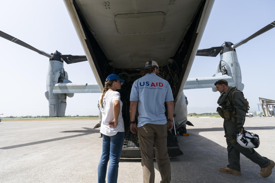 Aid workers stand after hygiene kits were loaded onto a VM-22 Osprey at Toussaint Louverture International Airport, Saturday, Aug. 28, 2021, in Port-au-Prince, Haiti. The VMM-266, "Fighting Griffins," from Marine Corps Air Station New River, from Jacksonville, N.C., are flying in support of Joint Task Force Haiti after a 7.2 magnitude earthquake on Aug. 22, caused heavy damage to the country. (AP Photo/Alex Brandon)