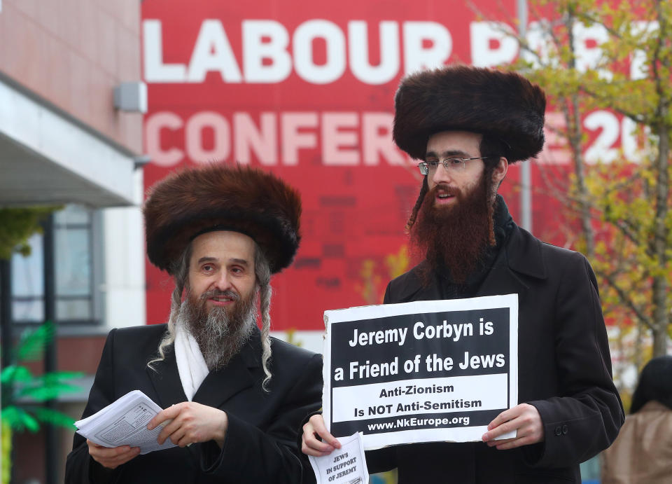 Two men wearing Orthodox Jewish attire hold placards and leaflets in support of Labour Party leader Jeremy Corbyn outside the party's conference in Liverpool, Britain, on Sept. 26, 2018.&nbsp; (Photo: Hannah Mckay / Reuters)