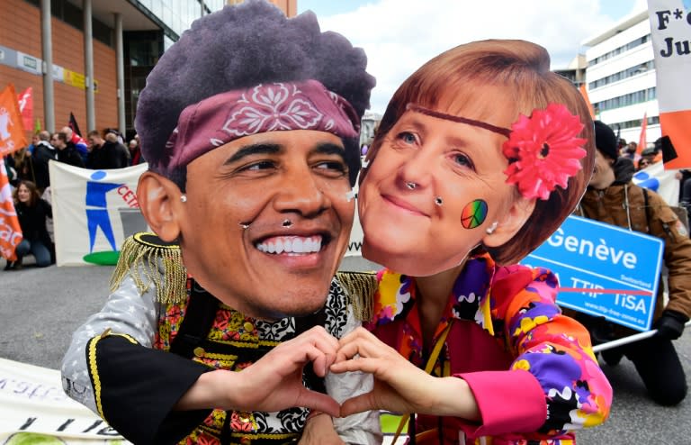 Protesters wearing masks of German Chancellor Angela Merkel and US President Barack Obama pose during a rally against the TTIP transatlantic trade deal on the eve of Obama's vist to Hanover on April 23, 2016