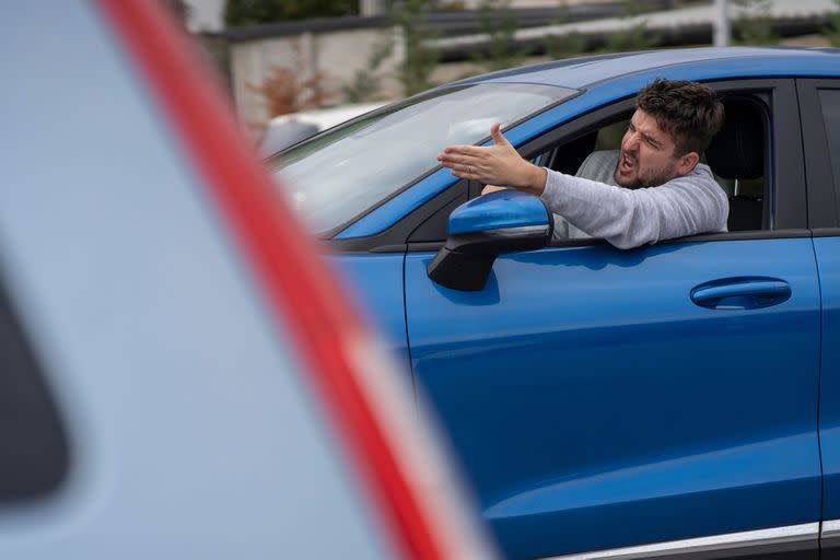 Angry man in the car in the queue yells at the driver in front. Side view