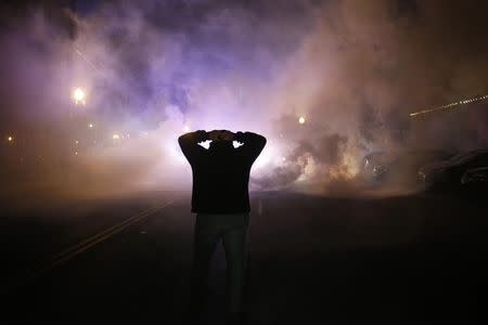 A protester stands with his hands on his head as a cloud of tear gas approaches after a grand jury returned no indictment in the shooting of Michael Brown in Ferguson, Missouri, November 24, 2014. REUTERS/Adrees Latif