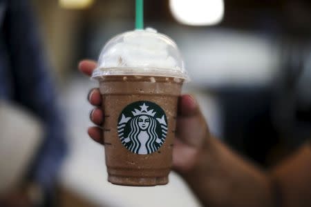 A woman holds a Frappuccino at a Starbucks store inside the Tom Bradley terminal at LAX airport in Los Angeles, California, United States, October 27, 2015. REUTERS/Lucy Nicholson