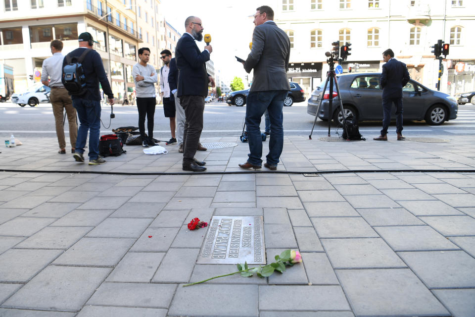 Reporters stand by a memorial plaque showing the place where Swedish Prime Minister Olof Palme was shot dead in February 1986, in Stockholm, Sweden, Wednesday, June 10, 2020. Sweden on Wednesday dropped its investigation into the unsolved murder of former Swedish Prime Minister Olof Palme, who was shot dead 34 years ago in downtown Stockholm because the main suspect, Stig Engstrom, had died in 2000. (Fredrik Sandberg/TT via AP)