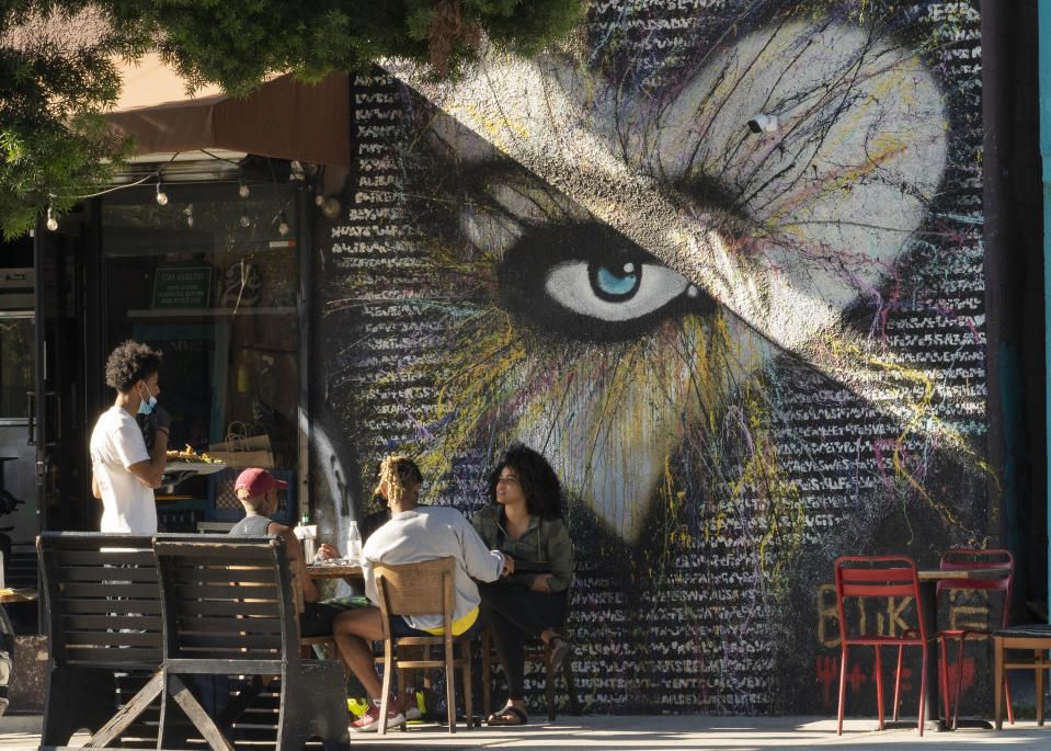 People eat outdoors outdoors at a soul food restaurant in Los Angeles on Saturday, Jun. 5, 2021. Most of California's coronavirus restrictions on businesses and public gatherings will end June 15. (AP Photo/Damian Dovarganes)