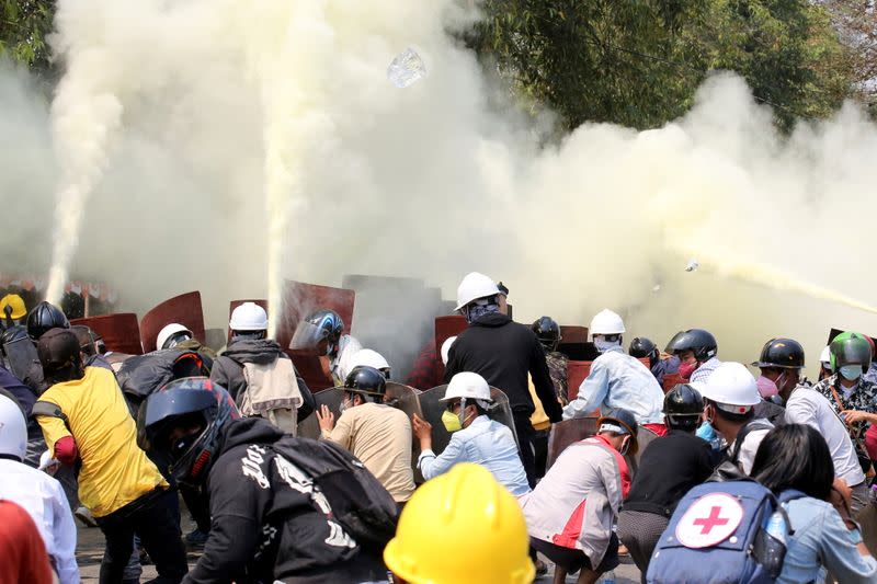 Tear gas and fire extinguisher gas float around demonstrators during a protest against the military coup in Naypyitaw