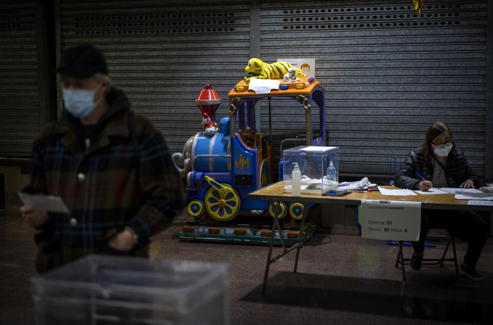 A man waits at a polling station set up in a market, before casting his vote for the regional Catalan election in Barcelona, Spain, Sunday, Feb. 14, 2021. Over five million voters are called to the polls on Sunday in Spain's northeast Catalonia for an election that will measure the impact of the coronavirus pandemic on the restive region's secessionist movement. (AP Photo/Emilio Morenatti)