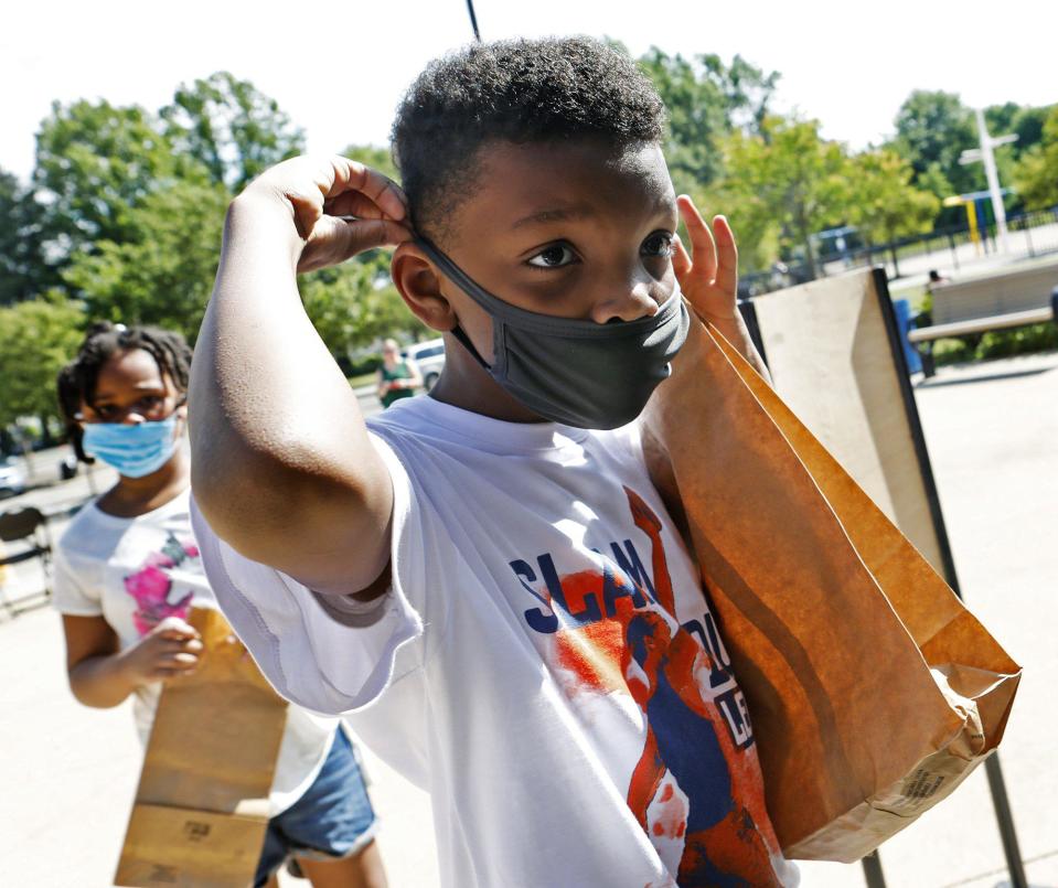 TyShawn Fowler, 8, puts on his face mask. The day camps don't require kids to wear face masks outdoors, but social distancing is adhered to.