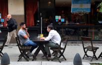 Two men sit down at a cafe outside the Stock Exchange in Buenos Aires' financial district, Argentina October 18, 2018. Picture taken October 18, 2018. REUTERS/Marcos Brindicci