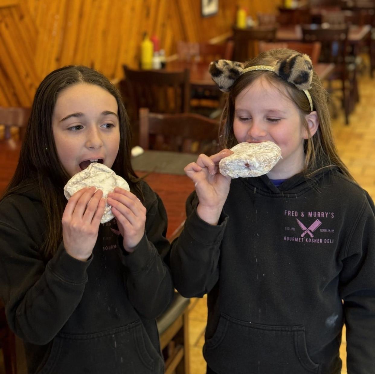 Addison Walther and Danielle Gerardo enjoying traditional sufganiyot for Hanukkah at Fred and Murry's Kosher Delicatessen in Freehold.