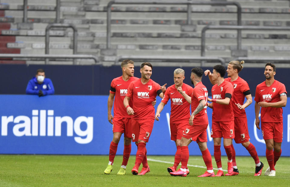 Augsburg's Eduard Loewen celebrates with teammates after scoring his side's opening goal during the German Bundesliga soccer match between FC Schalke 04 and FC Augsburg at the Veltins-Arena in Gelsenkirchen, Germany, Sunday, May 24, 2020. The German Bundesliga becomes the world's first major soccer league to resume after a two-month suspension because of the coronavirus pandemic. (AP Photo/Martin Meissner, Pool)