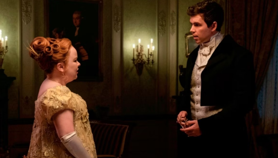Two characters from the series "Bridgerton" in a period room, the woman in an elaborate gown, the man in formal wear