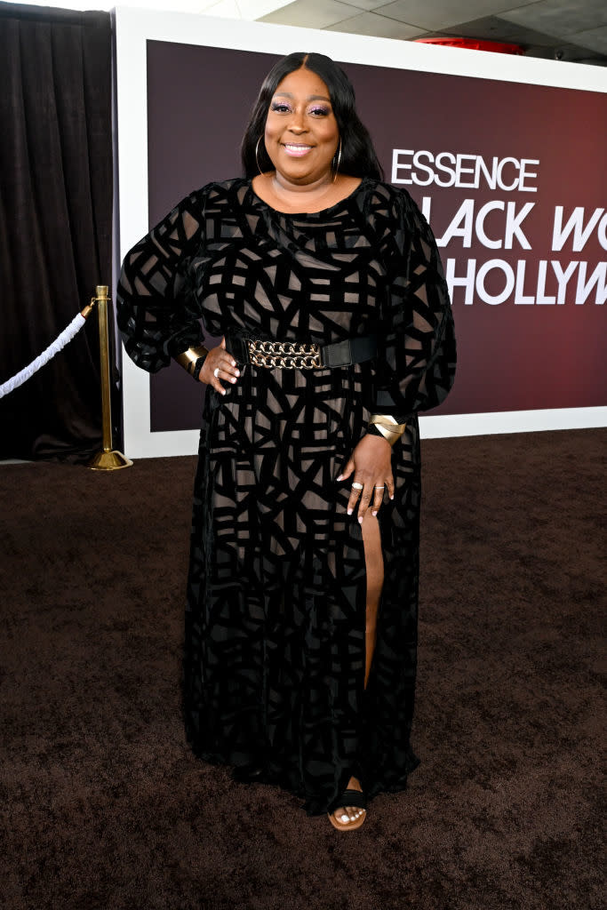 Loni in a patterned long-sleeved gown with side slit and belt accessory