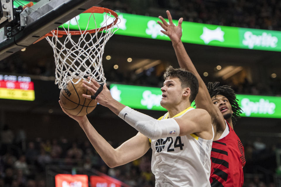 Utah Jazz center Walker Kessler (24) lays the ball up past Portland Trail Blazers guard Shaedon Sharpe during the second half of an NBA basketball game Saturday, Dec. 2, 2023, in Salt Lake City. (AP Photo/Isaac Hale)