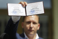 Andrei Dmitriyev shows his presidential candidate's identification card after he was registered as a candidate for the presidential elections in Minsk, Belarus, Tuesday, July 14, 2020. The election commission has cleared Belarusian President Alexander Lukashenko and four other candidates for running in a presidential vote in August, but denied registration to Lukashenko's two main aspiring challengers. (AP Photo/Sergei Grits)