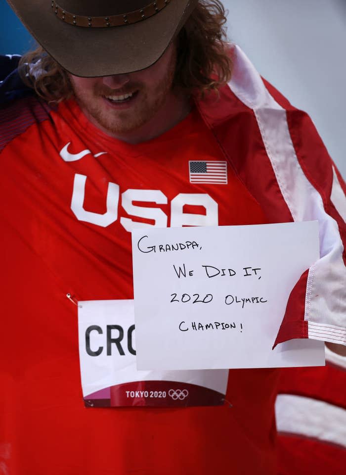 Ryan holds up a sign that says, "Grandpa, We did it, 2020 Olympic Champion!"