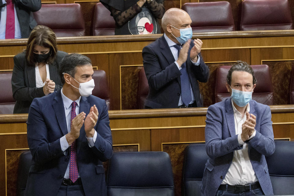 Spain's Prime Minister Pedro Sanchez, left and 2nd Deputy Prime Minister Pablo Iglesias applaud during a parliamentary session in Madrid, Spain, Thursday Oct. 22, 2020. Spanish Prime Minister Pedro Sanchez is facing a no-confidence vote in parliament brought by the nation's far-right Vox party. (Pablo Blazquez Dominguez/Pool via AP)