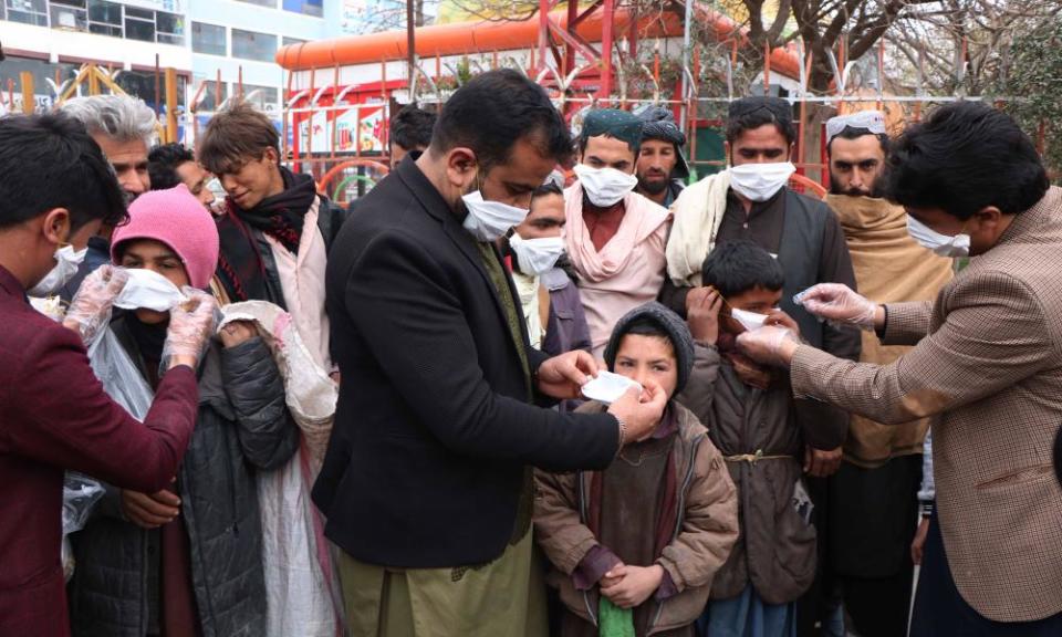 People distribute protective masks in Afghanistan after the war-torn country reported its first cases of the virus.