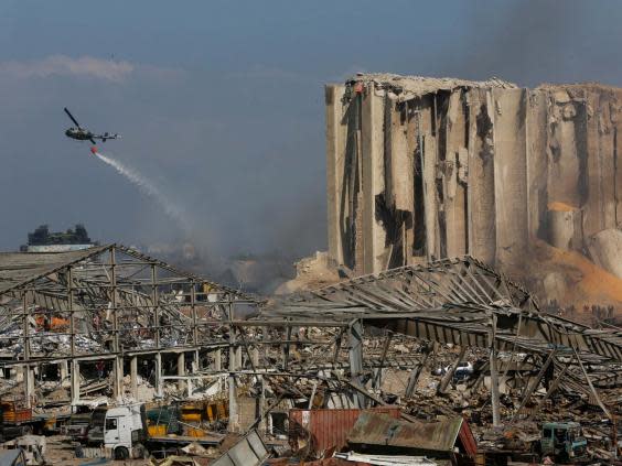 A helicopter drops water on smouldering buildings in Beirut’s port, destroyed by an explosion a day earlier. (Getty Images)