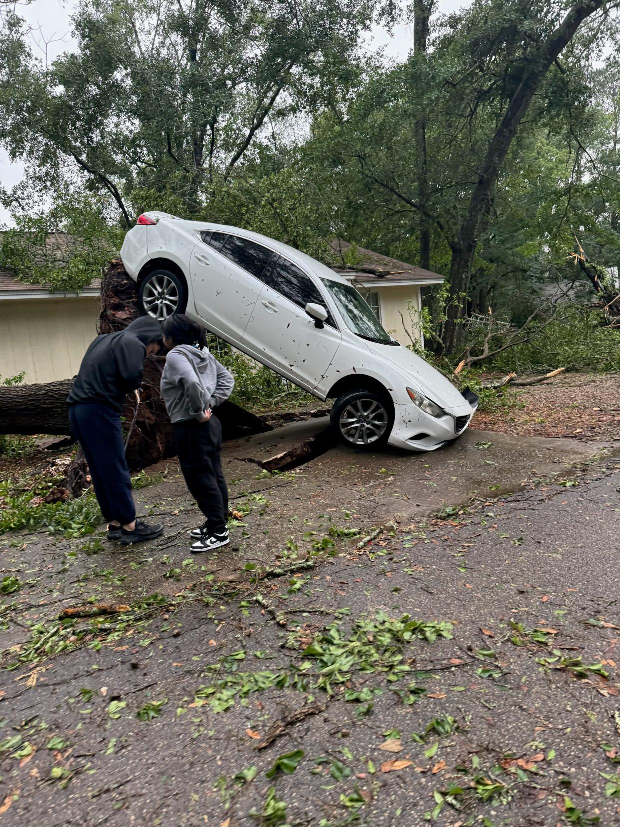 An uprooted tree pulled up the pavement and tilted a car along Tomahawk Trail Friday May 10, 2024