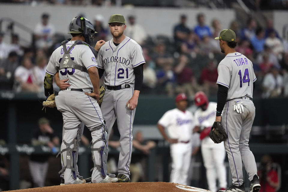 Colorado Rockies starting pitcher Kyle Freeland (21) stands on the mound with pitching coach Darryl Scott and catcher Elias Diaz (35) as shortstop Ezequiel Tovar (14) looks on during the first inning of a baseball game against the Texas Rangers in Arlington, Texas, Saturday, May 20, 2023. (AP Photo/LM Otero)