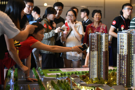 A woman points at the model of a residential compound by China Vanke as a sales agent introduces the property to the visitors at its showroom during the National Day "Golden Week" holiday, in Dongguan, Guangdong province, China October 2, 2018. REUTERS/Stringer