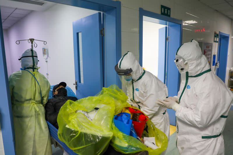 Medical workers in protective suits move a novel coronavirus patient at an isolated ward of a designated hospital in Wuhan