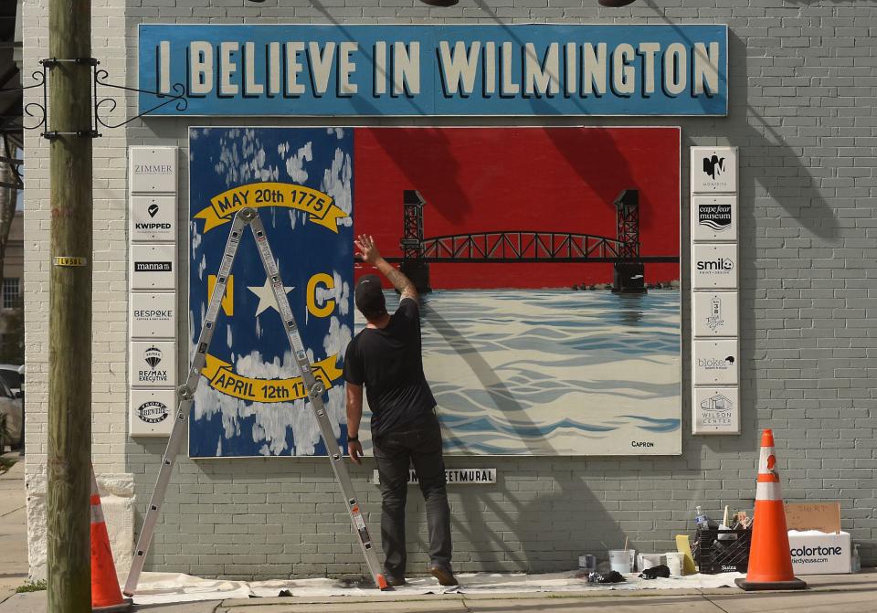 Ryan Capron touches up his "I Believe in Wilmington" painting at Second and Princess streets in 2021.